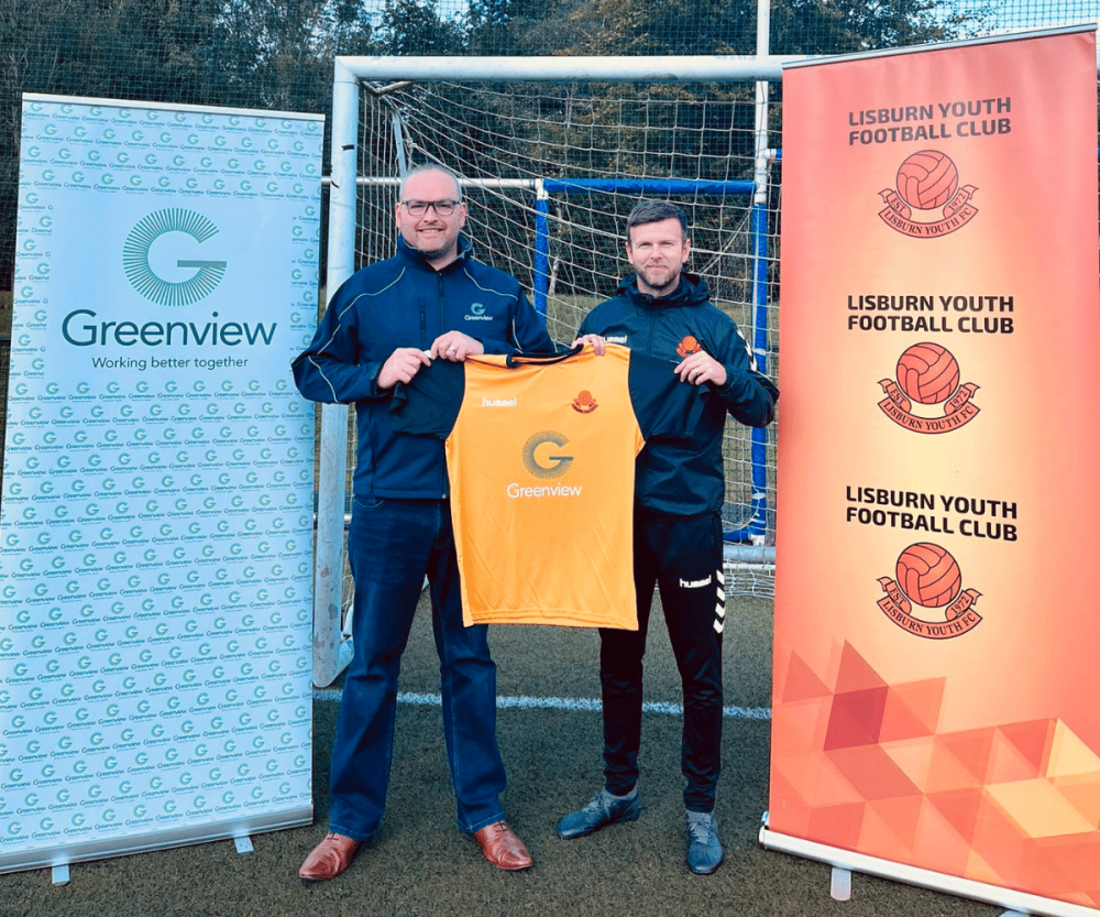 Image of Jonathan McCambley, Associate Director at Greenview, with Head Coach of Lisburn Youth Football Club, holding one of their new branded football tops.